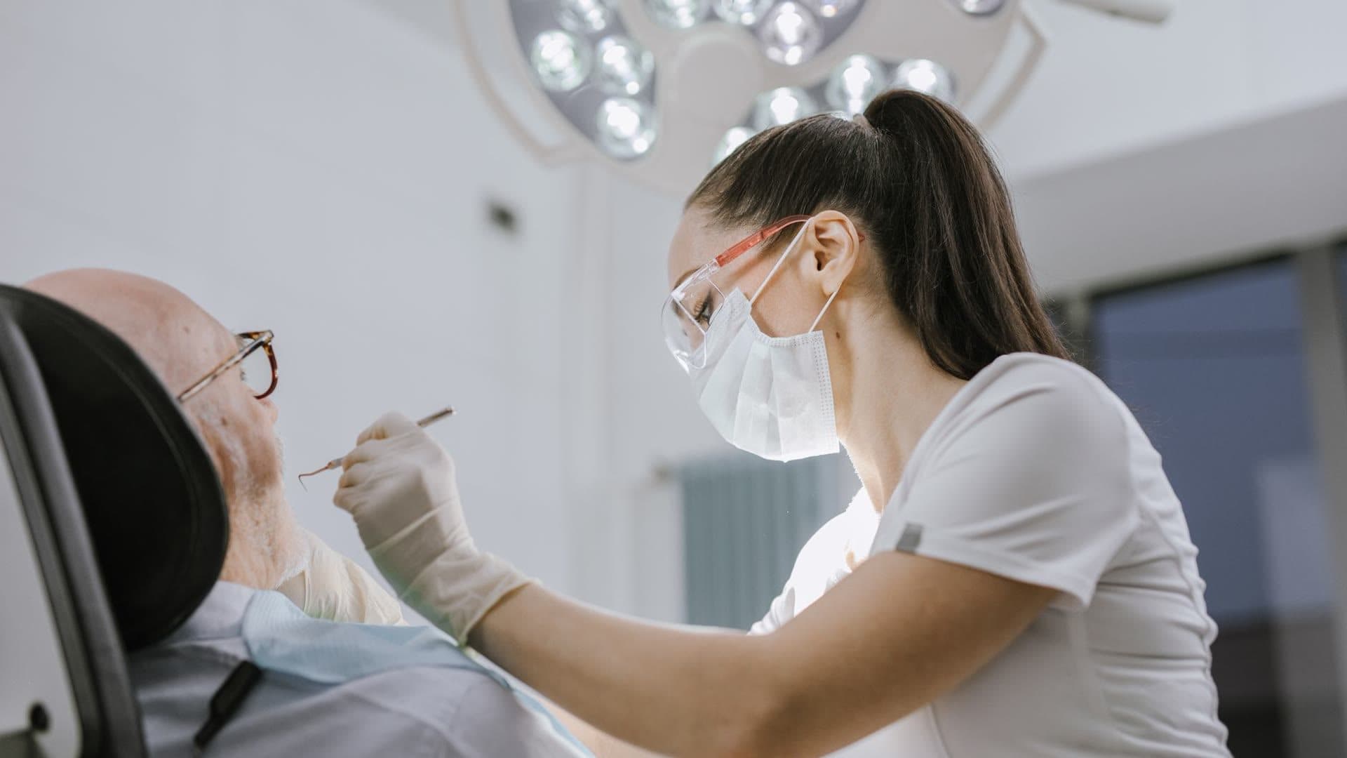 A dentist checks the teeth of an older patient.